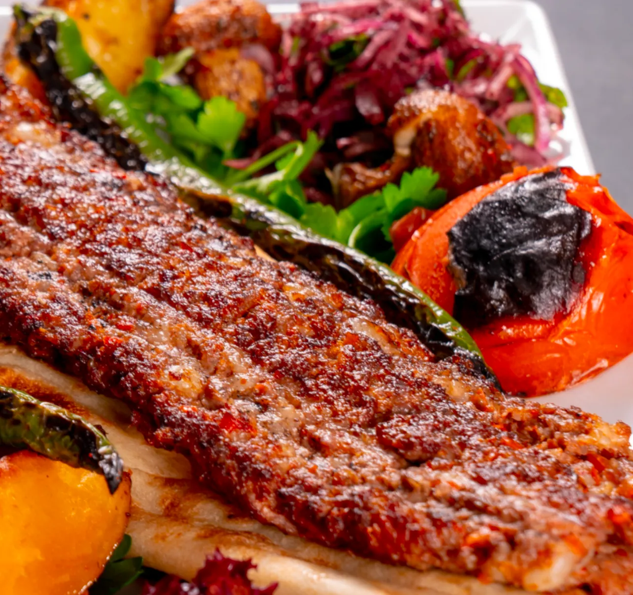 Adana Kebap - Adana'nın meşhur baharatlı kebabı, közde pişmiş, yanında közlenmiş biber ve domates ile servis edilir. Adana Kebap - Adana'nın meşhur baharatlı kebabı, közde pişmiş, yanında közlenmiş biber ve domates ile servis edilir.